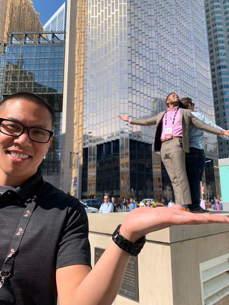 Teammate posing in a forced-perspective photo on a city plaza