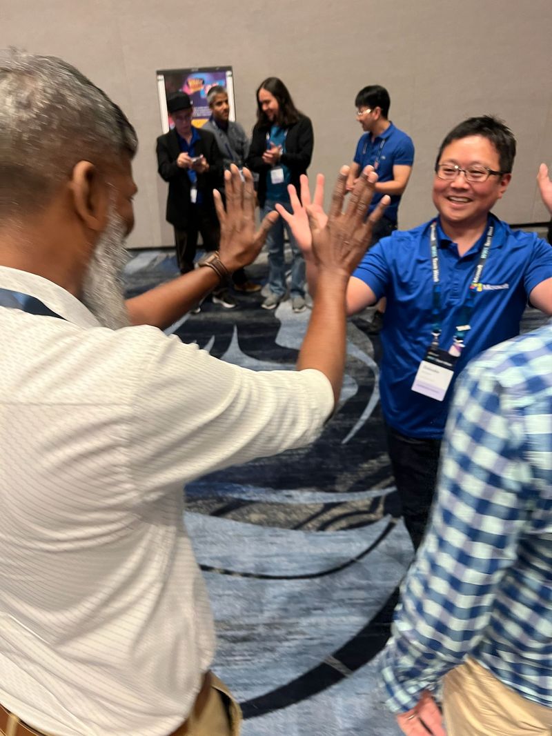 Teams celebrating with a high-five after an in-person poster game