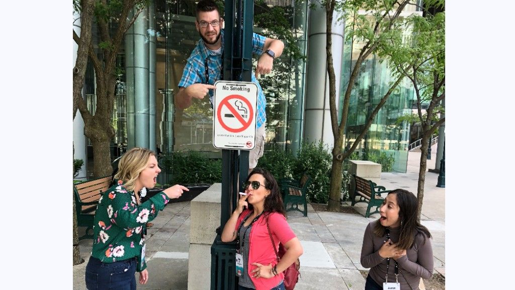 Team posing around a no-smoking sign during an Ultimate City Scavenger Hunt